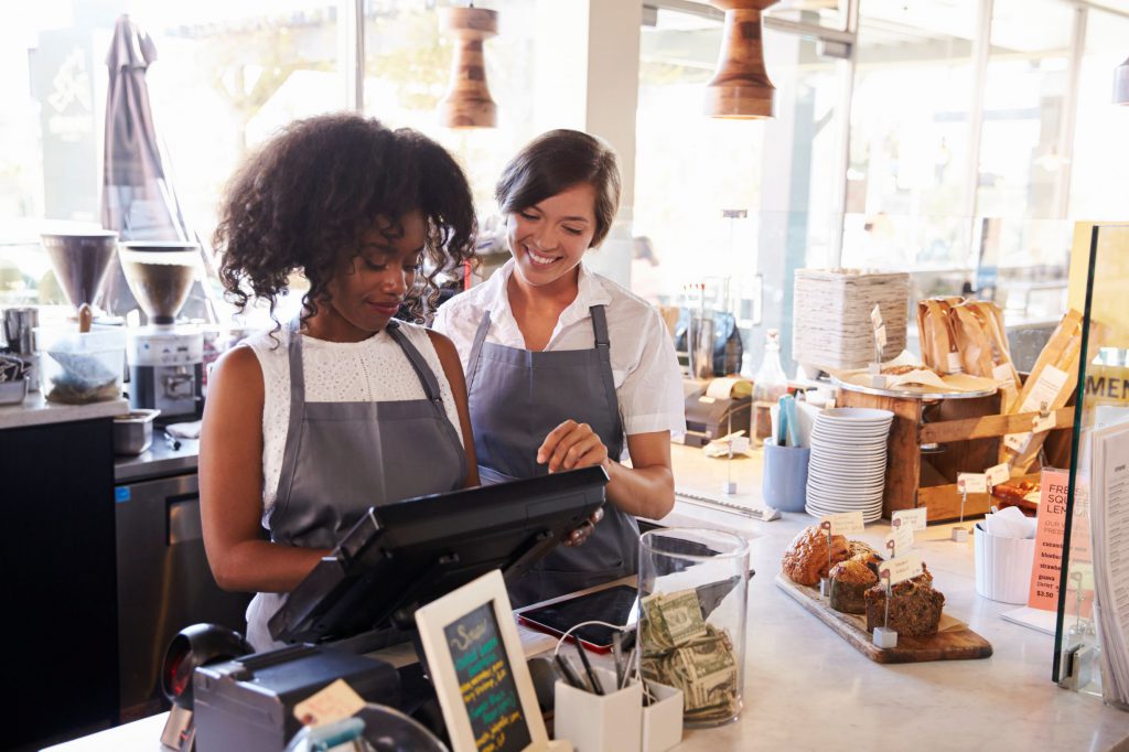 Business owner helping cashier with cash register